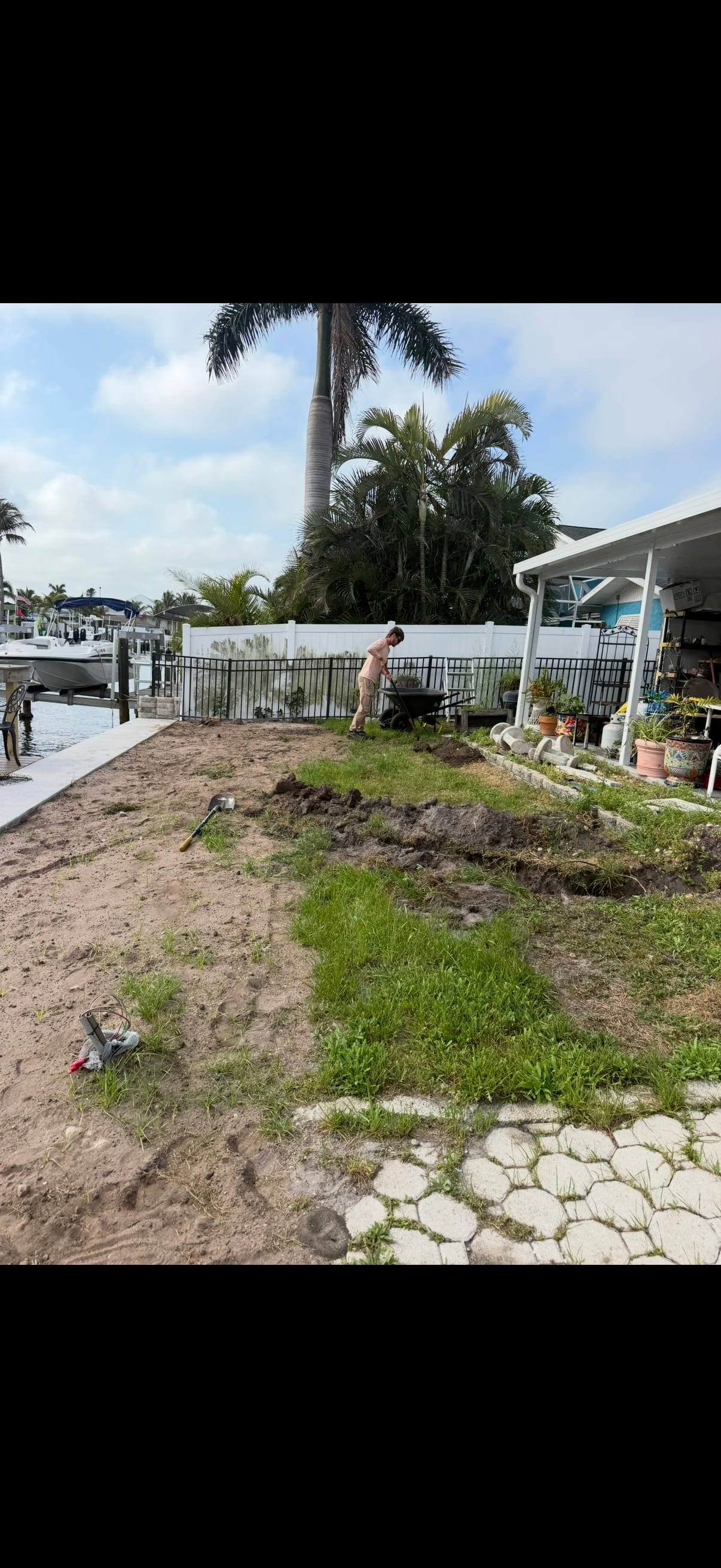 Before: the same waterfront backyard on dig day, with sand piles and tools by the seawall
