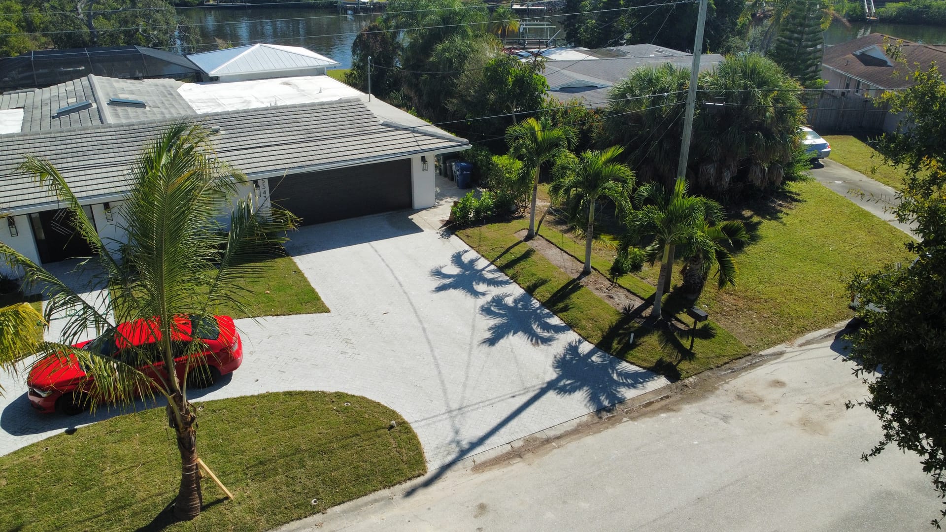 Waterfront home with paver driveway and palm trees framing the entrance