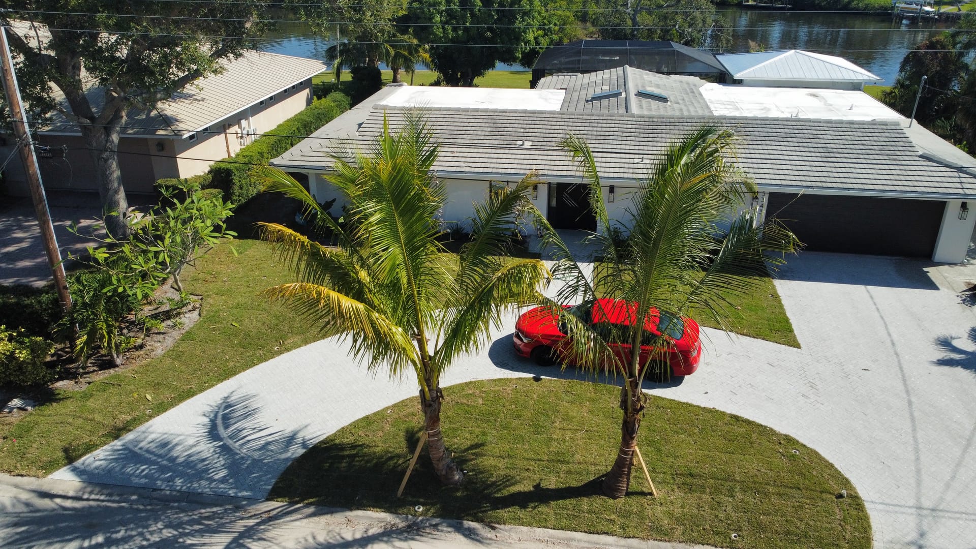 Aerial view of a waterfront Sarasota home with paver driveway and palm trees landscaped by Collica's Landscaping