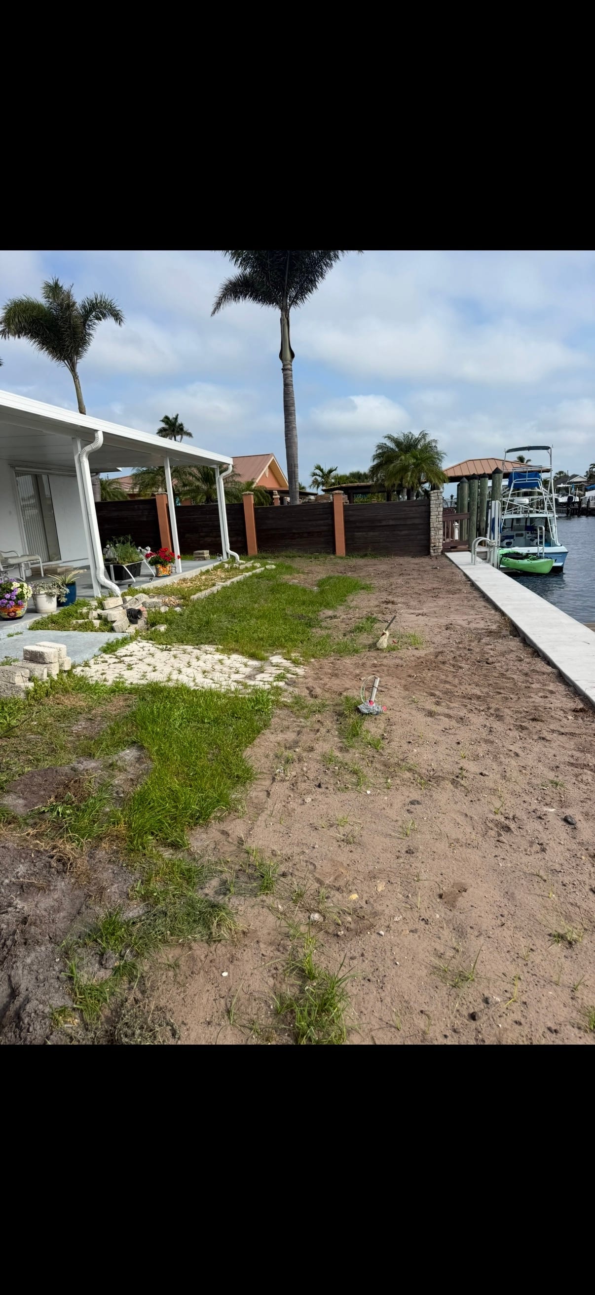 Before: patchy sandy waterfront backyard awaiting renovation
