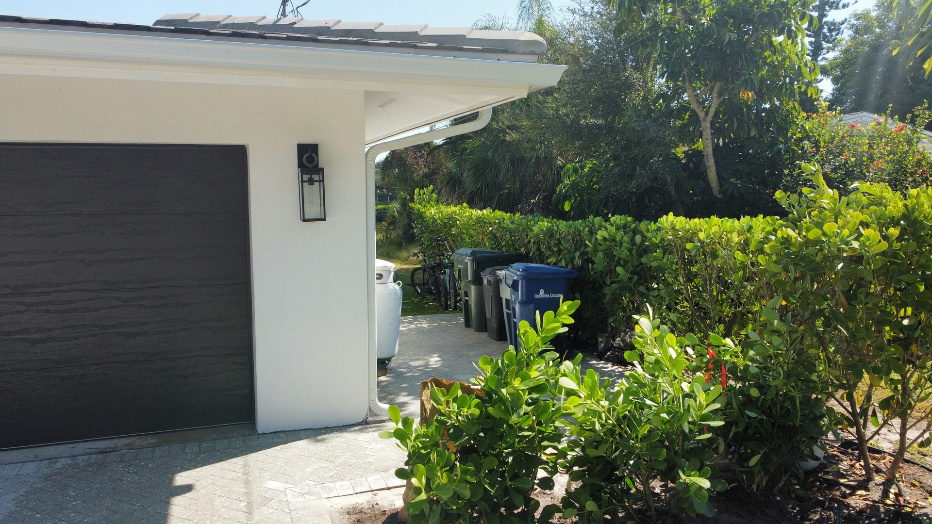 Home entrance with lush hedges and tropical shrubs along a paver driveway